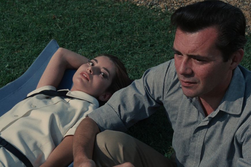 a woman lying on the grass looking at a man